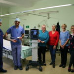 A photograph of theatre department staff accepting the ultrasound machine off four members of the League of Friends of Louth Hospital